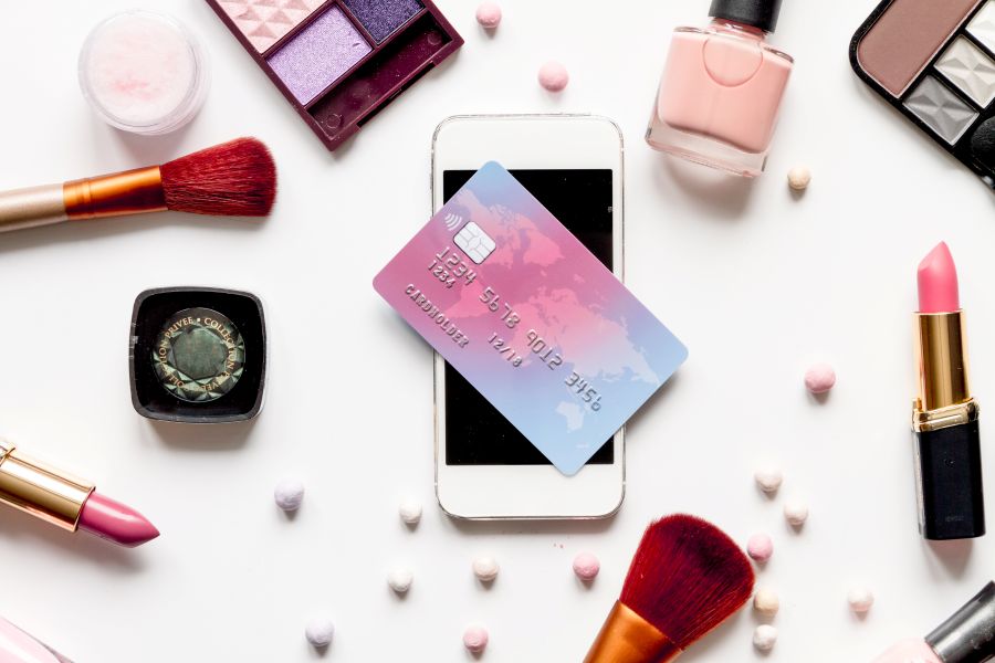 a mobile phone surrounded by cosmetics and a credit card